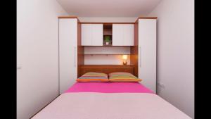 Dormitorio pequeño con cama con manta morada en ID Luxury Apartment, en Brela