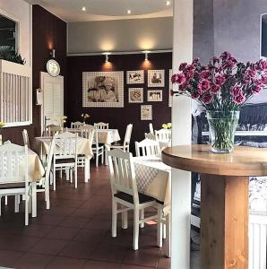 un restaurante con mesas y sillas y un jarrón de flores en Pokoje Przy Plaży, en Mielno