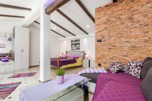 Una sala de estar con muebles morados y una pared de ladrillos. en Apartmani Hrvatin, en Opatija 84 fotos más