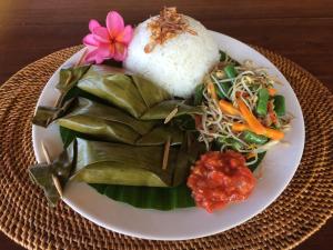 a plate of food with rice and vegetables on a table at Bali Segara Lestari Oceanfront Villas in Tejakula