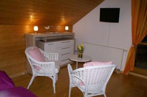 a living room with two chairs and a table and a tv at Vreni's Gästezimmer in Himmelried