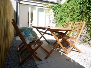 2 Stühle und ein Holztisch auf einer Terrasse in der Unterkunft The Gill Gardens Penthouse, Ulverston - Lake District in Ulverston