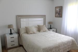 a bedroom with a white bed with two night stands and two lamps at Apartamento Datue in Elizondo