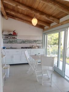 cocina blanca con mesa, sillas y ventana en Impietra, en Agropoli