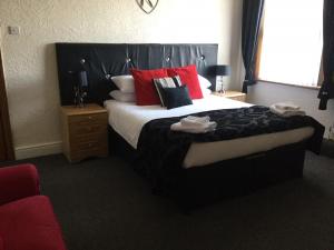 a bedroom with a large bed with red pillows at Woodlands Guest House in Liverpool