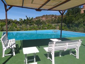 un patio con 2 sillas blancas y una piscina en Cabañas de San Bartolomé en Villahermosa del Río
