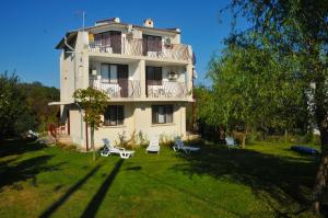 un gran edificio con un patio con sillas delante en Villa Velika - Slavi, en Velika