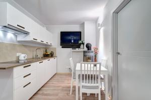 una cucina con armadi bianchi e tavolo con sedie di Apartament Jantar Park a Jantar