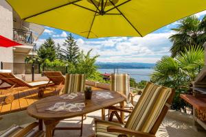 un patio con mesa, sillas y sombrilla amarilla en Apartmani Hrvatin, en Opatija