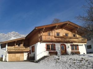 ein großes Holzhaus mit Schnee davor in der Unterkunft Koasa Chalet in Going