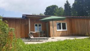 a patio with a table and an umbrella and a chair at Ferienbungalow Sonnenwald Bayerischer Wald in Schöfweg
