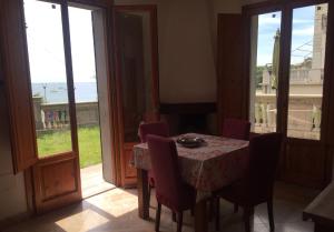 a dining room with a table and chairs and windows at Appartamenti fronte mare in Castiglioncello