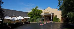 a restaurant with tables and umbrellas in front of a building at Hamlet Court Hotel in Enfield