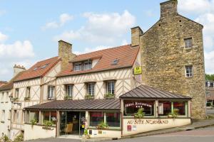 an old stone building with a store in front of it at Logis Hotel Au Site Normand in Clécy