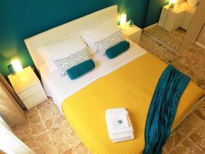 - une chambre avec un grand lit jaune et des serviettes dans l'établissement Corte Degli Aranci House, à Paterno