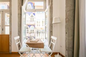 een eetkamer met een tafel en stoelen en een raam bij Stay in Apartments - S. Bento in Porto