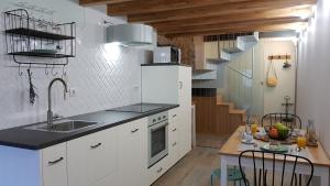 a kitchen with white cabinets and a sink and a staircase at A Casiña de Dina in Finisterre