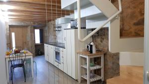 a large kitchen with white cabinets and a table at A Casiña de Dina in Finisterre +13 photos