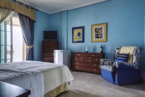 - une chambre avec des murs bleus, un lit et une chaise dans l'établissement Hotel La Colina, à Morro del Jable