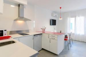 a kitchen with white cabinets and a pink counter top at NS Apartaments in Tossa de Mar