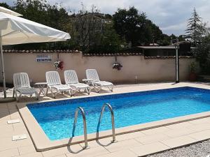 a swimming pool with chairs and a table and an umbrella at Apartments Sandra in Poreč
