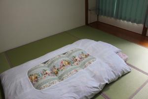 a bed with a blanket on top of it at Yamakyuso in Otari