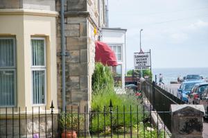 a building with a fence next to the ocean at Lomond Guest House in Leven