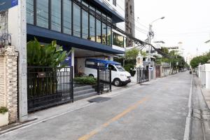 una calle vacía con una furgoneta blanca estacionada frente a un edificio en Apartelle Jatujak Hotel, en Bangkok