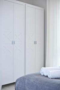 a bedroom with white cabinets and a bed with two towels at Apartamenty Porto Eli in Rowy