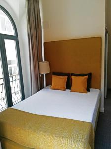 a bedroom with a bed with orange pillows and a window at Day Off Suite&Hostel in Setúbal