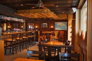 a bar with wooden tables and chairs in a restaurant at Hotel Des Alpes in Kandersteg