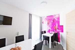 a dining room with a table with chairs and a pink painting at Villa Nova in Białystok