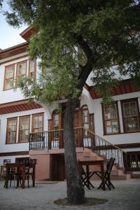 a table and chairs in front of a building with a tree at Melekli Konak in Amasya