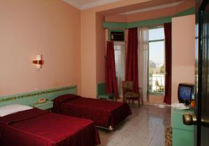una camera d'albergo con due letti e una televisione di Hotel Splendid a Fes
