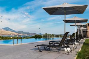 a group of chairs and umbrellas next to a swimming pool at Phaedra Suites in Lixouri