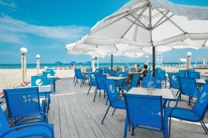 a beach with blue chairs and tables and white umbrellas at Ensenada in Gribovka