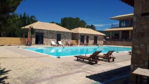 a swimming pool with chairs and a house at Almyra Holiday Village in Edipsos