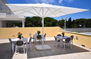un patio con mesas y sillas bajo una sombrilla blanca en Villa Luigia Luxury Relais en Gallipoli