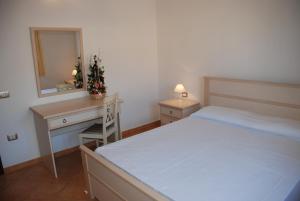 una camera con letto, scrivania e specchio di Li Troni a Budoni