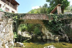 uma velha ponte de pedra sobre um riacho de água em El Molino em Arenas de Cabrales
