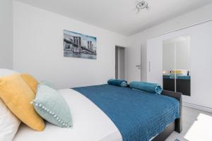 a white bedroom with a bed with pillows at Apartments HIPERION in Zadar