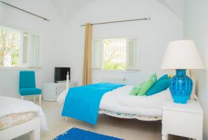 Dormitorio blanco con cama azul y lámpara azul en Villa"Dar Janna", en Hammamet