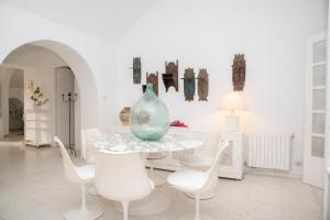 Habitación blanca con mesa, sillas y jarrón en Villa"Dar Janna", en Hammamet