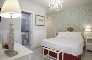1 dormitorio con cama blanca y lámpara de araña en Basic Hotel Puerta de Sevilla, en Sevilla