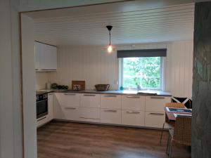 una cocina con armarios blancos y una ventana en North Cape family lodge, en Skarsvåg