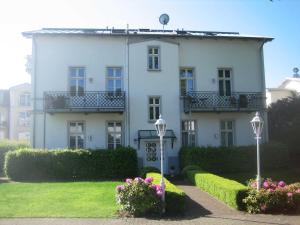 Villa Baroni BF nur 200m vom Ostseestrand entfernt في بانسين: أمامه بيت أبيض كبير وبه زهور