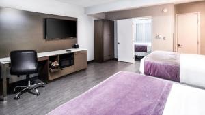 a hotel room with a bed and a desk and a tv at Sunset West Hotel, SureStay Collection By Best Western in Los Angeles