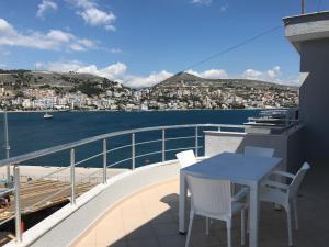 a table and chairs on a balcony with a view of the water at Kristina Bellavista Rooms in Sarandë
