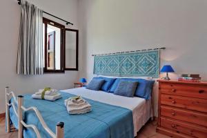 Schlafzimmer mit einem Bett mit blauer Bettwäsche und einer Kommode in der Unterkunft Il Melo Residence in Porto Torres