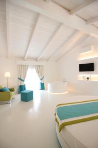 Il Borghetto Creative Resort في تروبيا: غرفة نوم بيضاء مع سرير كبير وحوض استحمام